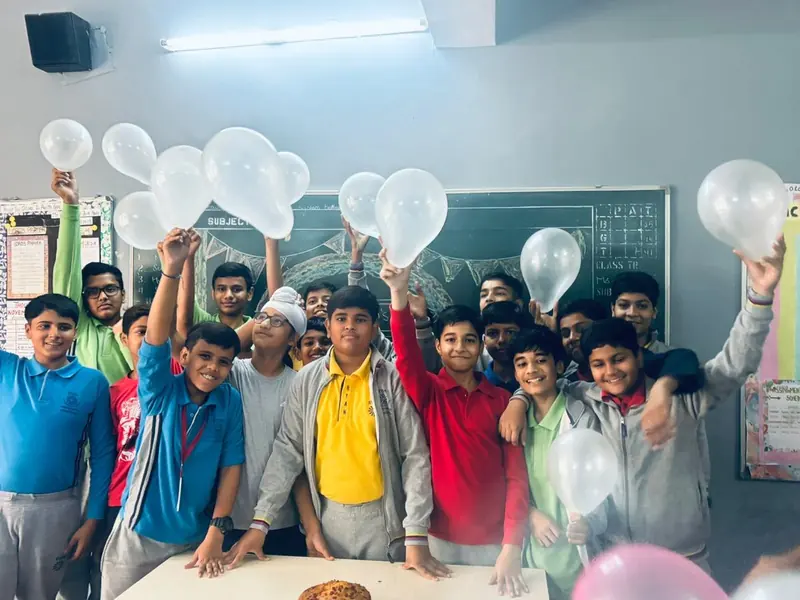 A class of boys cheering and holding up white balloons