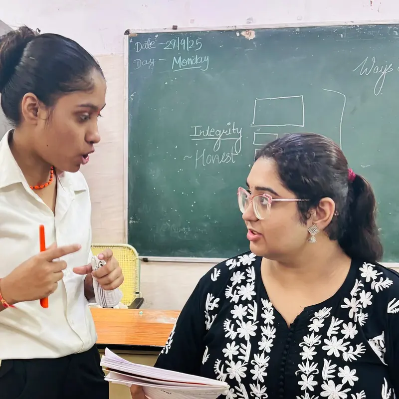 A teacher in conversation with a student in front of a chalkboard