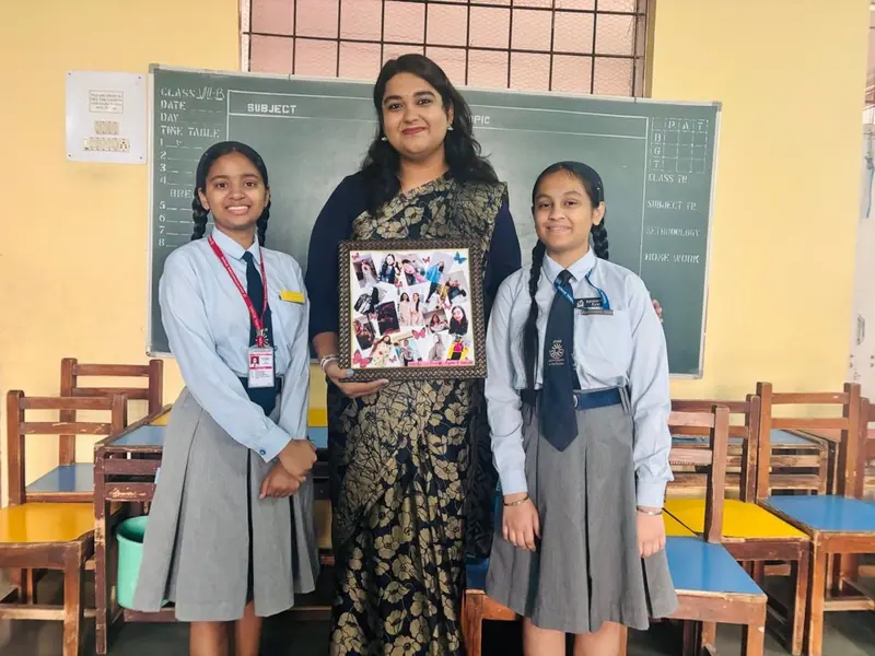 Two students and their TalkTheTalk teacher holding up a framed photo collage