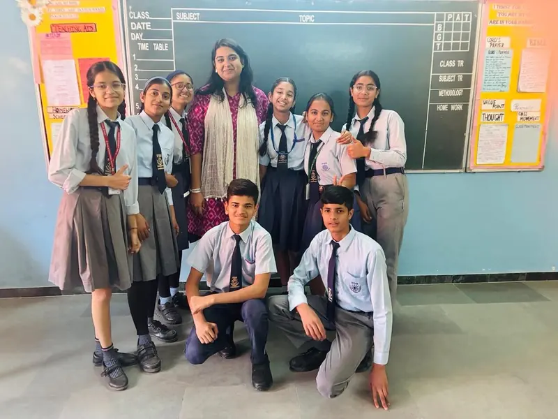 A school group posing with their TalkTheTalk teacher at the chalkboard
